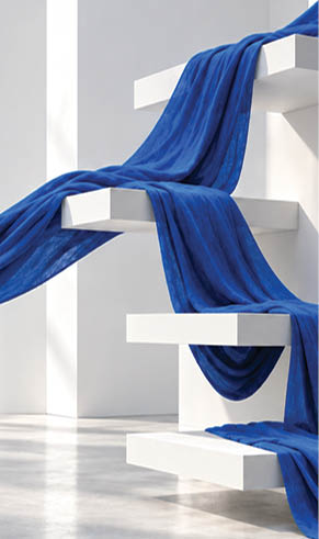 A flowing blue fabric is draped and stretched across white geometric shelves in a minimalist, well-lit space with a smooth concrete floor. Description generated by AI